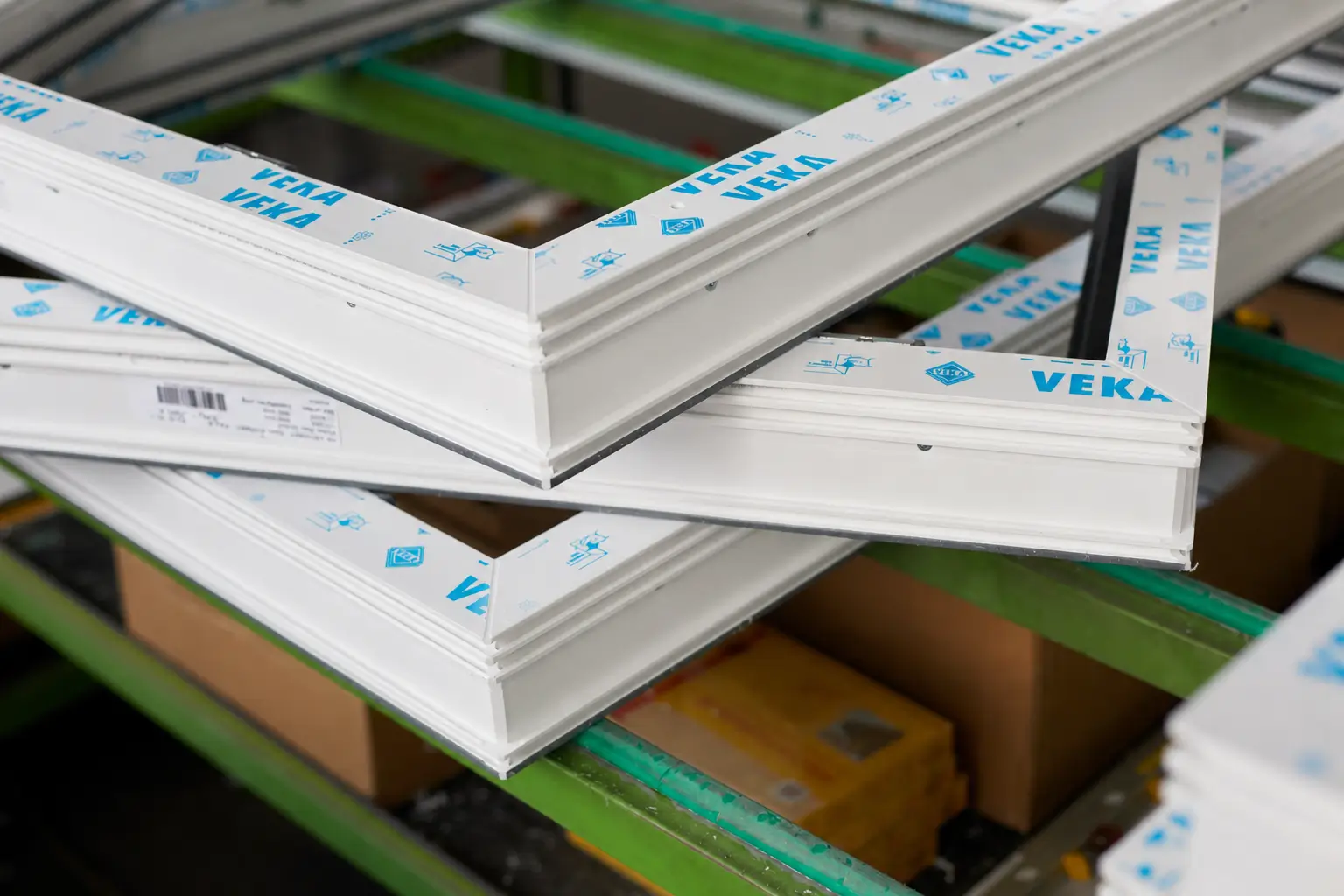 Mehrere weiße Fensterrahmen mit blauer Aufschrift VEKA übereinander gestapelt