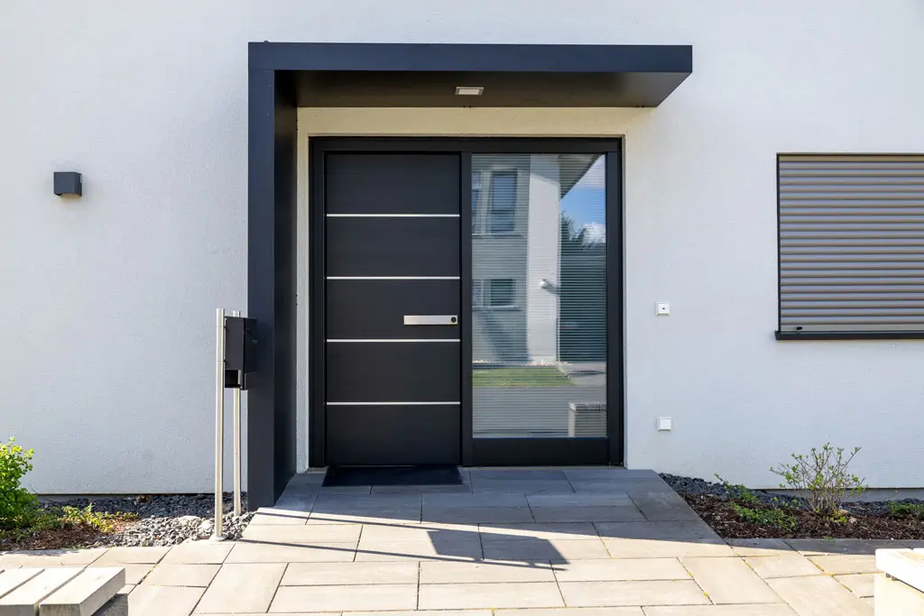 Moderner Hauseingang mit schwarzer Tür, großem Seitenfenster und grauem Putz