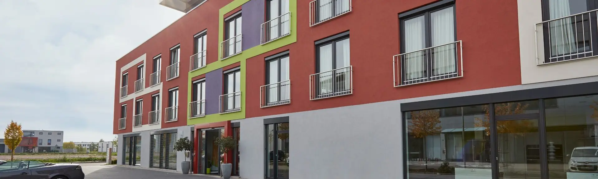 Mehrstöckiges modernes Gebäude mit rechteckigen Fenstern und Balkonen an der Fassade