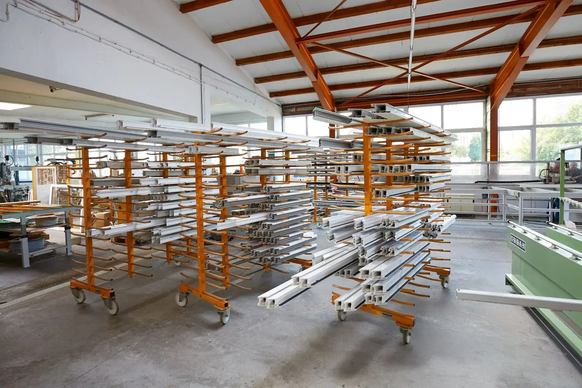 Lagerhalle mit mehreren orangefarbenen Metallgestellen, die weiße Fensterrahmen halten