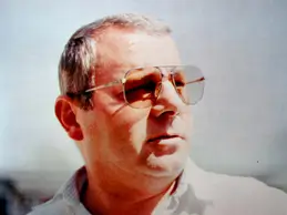 Porträt eines Mannes mit kurzen Haaren und Sonnenbrille, der nach rechts blickt